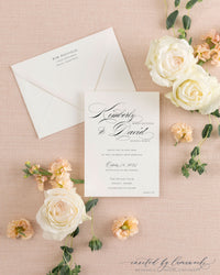 The Kim - Classic Calligraphy suite's reception card and wedding invitation shown together on pink linen with white roses