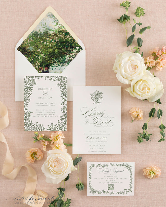 Flatlay of the Kim wedding invitation suite, including a botanical envelope liner, reception card, and calligraphy invitation, styled with garden roses on pink linen