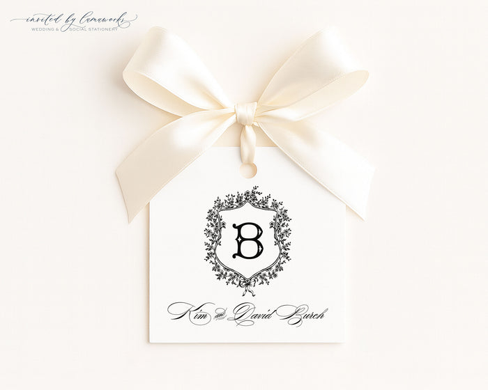 The Kim collection square gift tag with a monogram crest and the couple's full names in script, tied with a cream ribbon bow