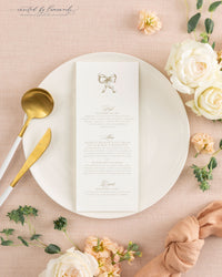 The Kim wedding menu card in gold ink, plated with gold flatware and a knotted peach napkin