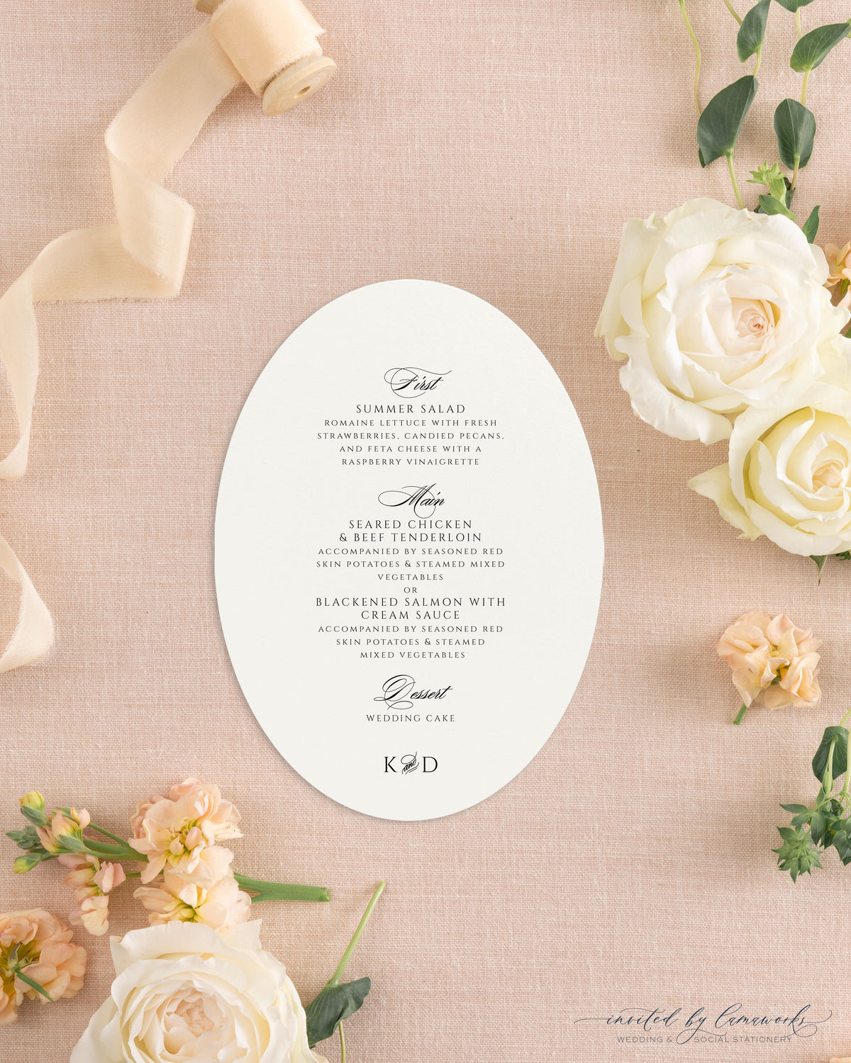 The Kim collection oval die cut wedding menu card in black ink with calligraphy course headers and a K and D monogram, styled with peach ribbon and roses