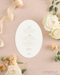 The Kim collection oval die cut wedding menu card in gold ink with calligraphy course headers and a K and D monogram, styled with peach ribbon and roses