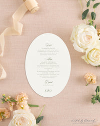 The Kim collection oval die cut wedding menu card in sage green ink with calligraphy course headers and a K and D monogram, styled with peach ribbon and roses