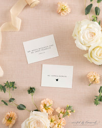 The Kim collection place and escort cards on pink linen with peach ribbon and roses, showing a guest name with meal icon and a couple's names with table number
