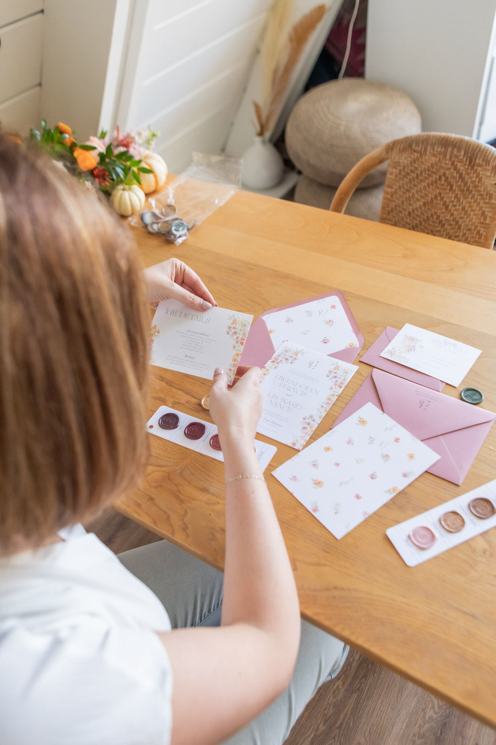 Laura Mays sits at a table looking through invitation pieces, checking them for quality.