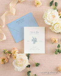 The Kim collection save the date card with a hand-illustrated floral bouquet monogram in blue ink, paired with a matching dusty blue envelope