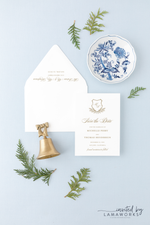 Christmas wedding save the date in gold with a monogram evergreen crest
